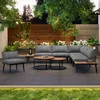 A modern outdoor lounge set with a sectional sofa, armchair, and coffee tables on a patio with lush greenery in the background. Produktbild-Vorschau