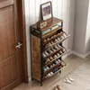 A shoe cabinet with multiple shelves is shown in a hallway next to a wooden door. The cabinet is filled with shoes, and a framed picture and a radio are on top. Náhľad obrázku produktu