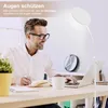 A man is working at a desk with a laptop and a notebook, illuminated by a floor lamp. Produktbild-Vorschau