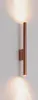 A copper-colored wall lamp mounted on a white wall, emitting light upwards and downwards. Náhled obrázku produktu