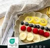 A bowl of oatmeal with fruit and a checkered tea towel. Produktbild-Vorschau
