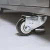 A close-up view of a caster wheel on a stainless steel appliance. Náhled obrázku produktu