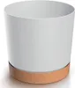 A white cylindrical planter with a brown base sits on a white surface. Produktbild-Vorschau