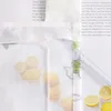 A close-up view of a white fabric with a lemon pattern, partially covering a book with text. Produktbild-Vorschau