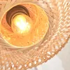 A close-up view of a woven bamboo lampshade with a lit light bulb inside. Anteprima dell’immagine prodotto