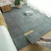 Graue ineinandergreifende Teppichfliesen werden auf einem Holzboden in einem Schlafzimmer verlegt, die Hände einer Person platzieren eine Fliese Anteprima dell’immagine prodotto