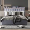 A bedroom scene featuring a bed with multiple pillows and a blanket. Produktbild-Vorschau