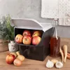 A storage container filled with apples, placed on a wooden surface with other vegetables and a bottle of liquid. Produktbild-Vorschau