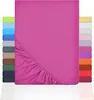 A pink fitted sheet is shown laid out, with a diagonal section of elasticized edge visible. To the left and right of the main sheet are stacks of fitted sheets in various colors, suggesting a range of available options. Produktbild-Vorschau