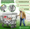 A man is pushing a wagon with two children inside, outdoors with greenery in the background. Produktbild-Vorschau