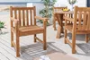 A wooden garden chair and table set on a wooden deck with a beach and ocean in the background. Produktbild-Vorschau