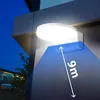 A white LED lamp is mounted on a building's exterior wall at night, with a blue cone indicating its light coverage area and a measurement of 9m. Voir les images du produit