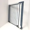 A gray metal safety gate is shown in a corner against a white wall. Voir les images du produit
