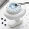A close-up shot of a white anti-cellulite massage device with a light blue top, being used with tweezers to pick up a small black disc. Anteprima dell’immagine prodotto
