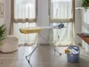 A room with an ironing board, iron, and laundry basket, with windows and curtains in the background. Náhľad obrázku produktu