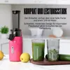 A pink juicer is shown on a countertop with two glasses of juice and some produce. Náhled obrázku produktu