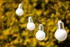 A string of solar-powered light bulbs hanging in front of a blurred yellow-green bush. Náhľad obrázku produktu