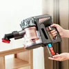 A hand holds a cordless vacuum cleaner with a brush attachment. Produktbild-Vorschau