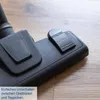 A close-up of a black vacuum cleaner attachment on a wooden floor. Anteprima dell’immagine prodotto