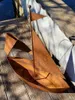 A rusty metal boat planter sits on a wooden deck next to a white wall. Produktbild-Vorschau