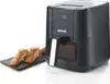A black Gorenje air fryer is shown next to a slate with cooked salmon. Produktbild-Vorschau