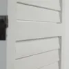 A close-up view of a white wooden room divider with horizontal slats. Produktbild-Vorschau