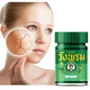 A woman's face with a magnified view of dry, cracked skin is shown next to a green jar of herbal balm. Produktbild-Vorschau