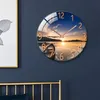 A round wall clock with a sunset landscape image is mounted on a dark blue wall above a gold bed frame. Voir les images du produit