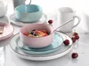 A collection of ceramic tableware, including bowls and mugs, set on a white surface with cherries scattered around. Náhľad obrázku produktu