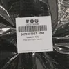 A close-up of a product label on a black, textured item, likely a car mat, inside clear plastic packaging. Produktbild-Vorschau