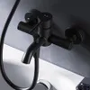 A close-up shot of a black bathtub faucet mounted on a gray wall, with a white bathtub visible below. Produktbild-Vorschau