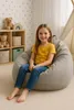 A young girl sits on a beanbag chair in a child's room. Produktbild-Vorschau