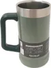 A close-up studio shot of a green Stanley insulated mug with a silver rim and a dark green handle. Voir les images du produit
