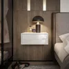 A modern bedroom scene with a bedside table, lamp, and perfume bottles. Produktbild-Vorschau