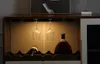 A close-up view of a wine cabinet with two wine glasses hanging, a bottle of wine, and a bottle of liquor. Podgląd zdjęcia produktu