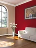A living room with a red accent wall, a large arched window, a white sofa, and a vase of white flowers. Produktbild-Vorschau