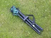 A folded camping stool with a carrying strap lies on a grassy lawn. Voir les images du produit