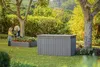 A garden scene with a storage box and raised garden beds, featuring two people. Podgląd zdjęcia produktu