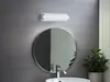 A bathroom vanity with a round mirror, a wall-mounted light fixture, and a sink. Náhled obrázku produktu