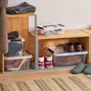 Storage boxes filled with shoes and clothing, organized on shelves. Produktbild-Vorschau