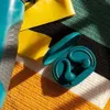 A pair of teal wireless earbuds in their charging case are placed on a striped towel, next to yellow swim fins and a blue water bottle. Anteprima dell’immagine prodotto