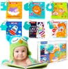 A baby wearing an owl hat lies on a book, surrounded by colorful baby cloth books. Anteprima dell’immagine prodotto