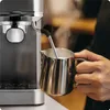A person is using a coffee machine to froth milk in a metal pitcher. Anteprima dell’immagine prodotto