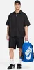 A man wearing a black Nike outfit and holding a blue Nike backpack. Voir les images du produit