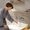 A woman in a bathrobe is checking the temperature of bathwater in a bathtub. Anteprima dell’immagine prodotto