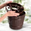 Hands assembling a brown Christmas tree stand that resembles a barrel. Voir les images du produit