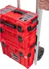 A person's hand is holding the handle of a rolling tool cart with stacked red toolboxes. Produktbild-Vorschau