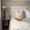 A cozy bedroom scene with a neatly made bed, pillows, a lamp, and a book. Produktbild-Vorschau