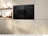 A black built-in microwave oven is shown installed in a modern kitchen with light-colored cabinets. Náhľad obrázku produktu