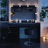 A vanity table with LED lights and a stool, set in a room with windows showing a snowy mountain landscape at night. Náhled obrázku produktu